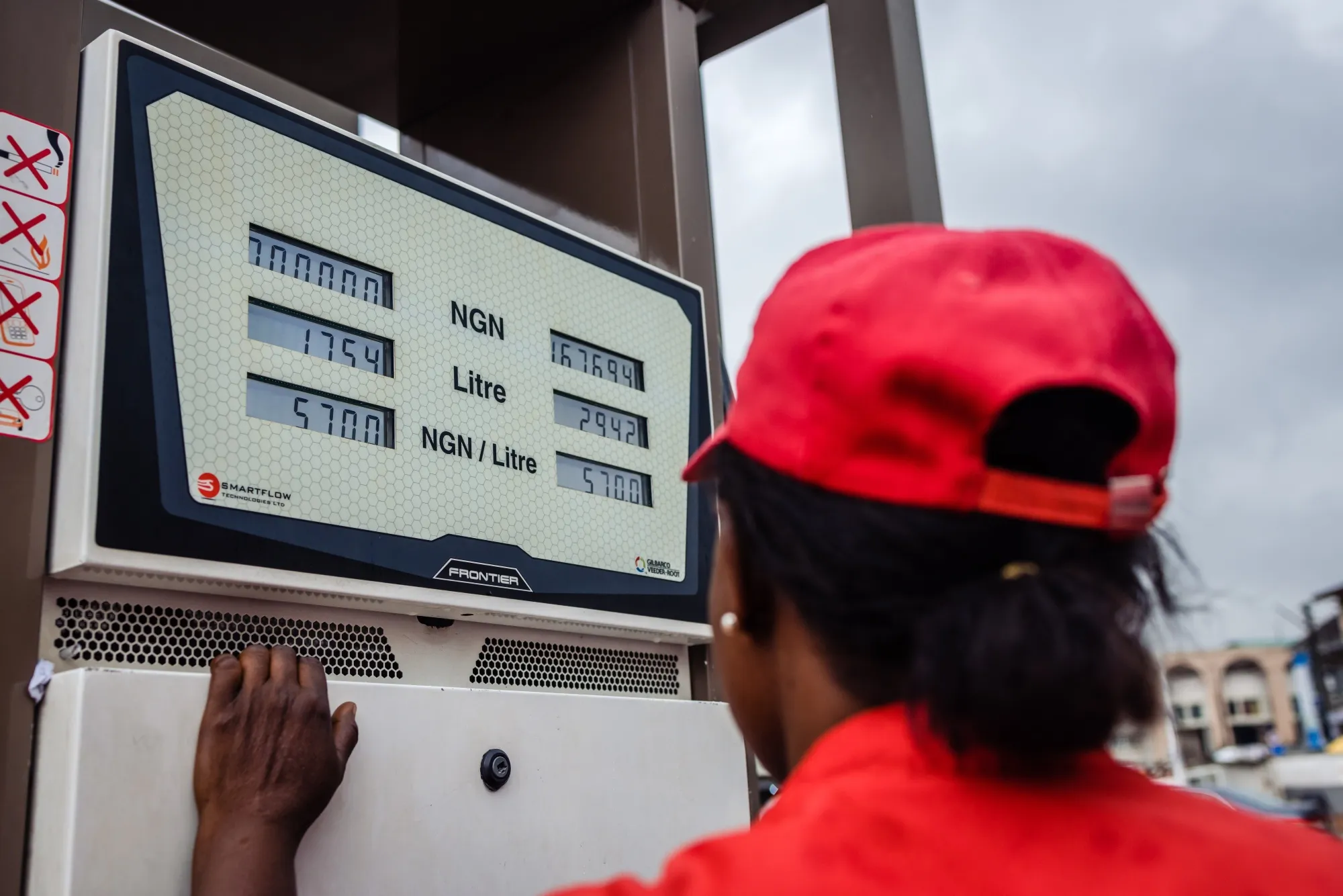 A fuel attendant monitors the meter as they refuel a customer's vehicle in Lagos, Nigeria.