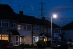 An electricity transmission tower near residential houses with lights on in Upminster, UK, on&nbsp;July 4.