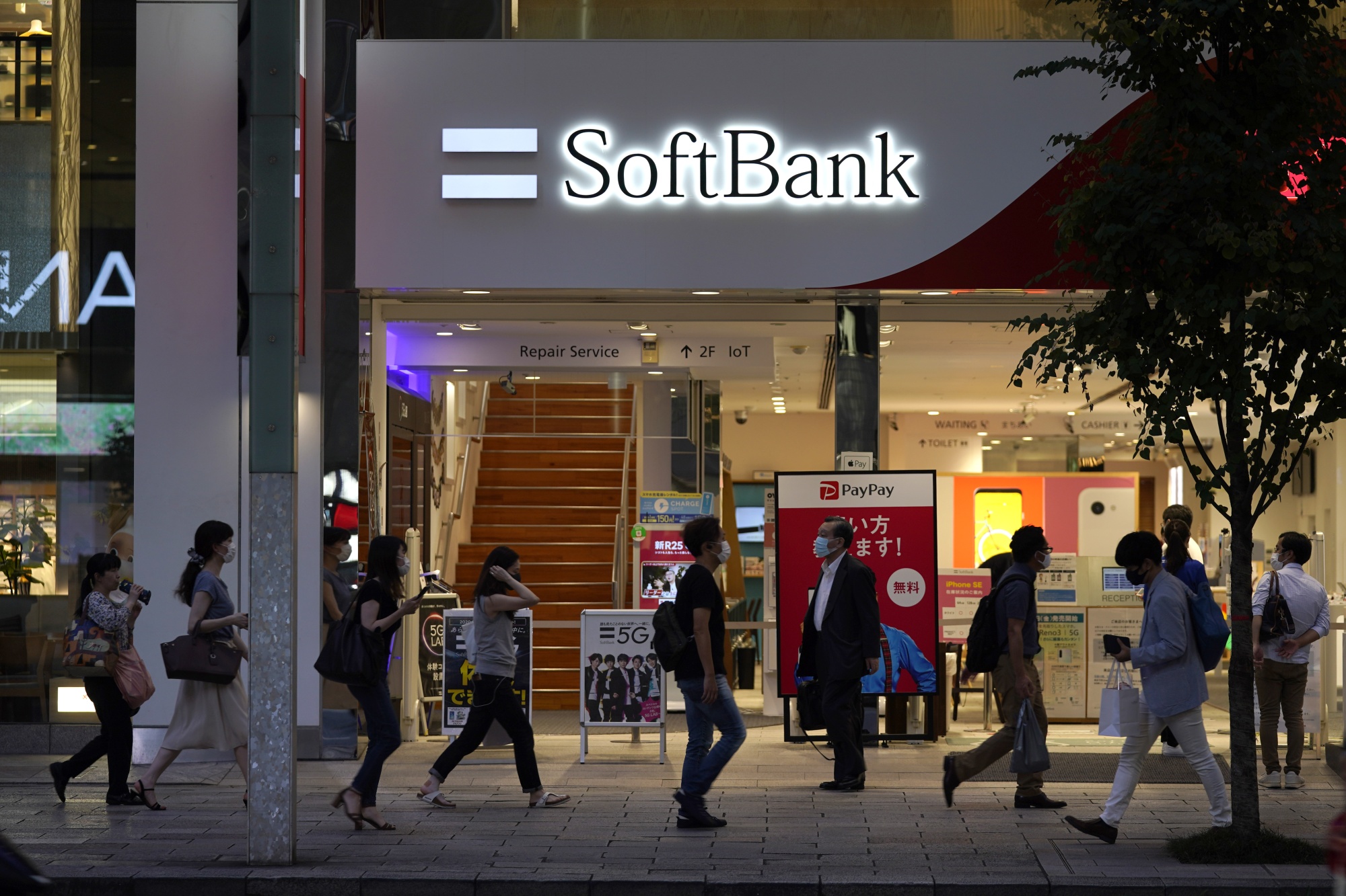 Pedestrians walk past a SoftBank Corp. store in Tokyo.