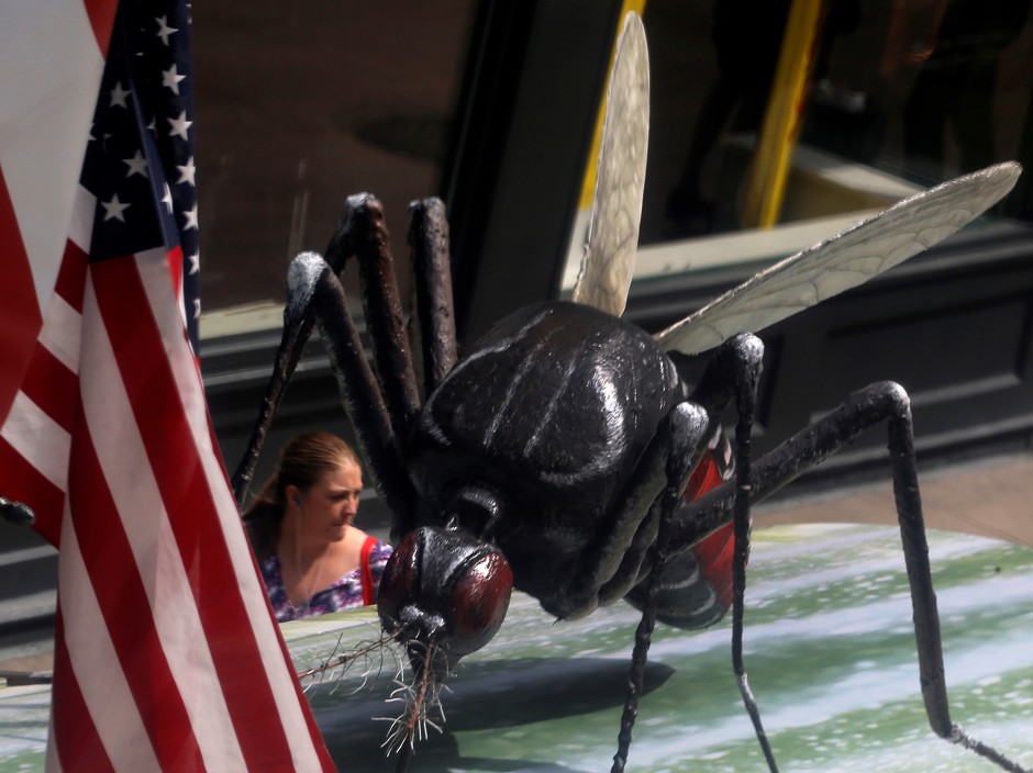 A woman walks past a giant fake mosquito placed on top of a bus shelter as part of an awareness campaign about the Zika virus in Chicago.