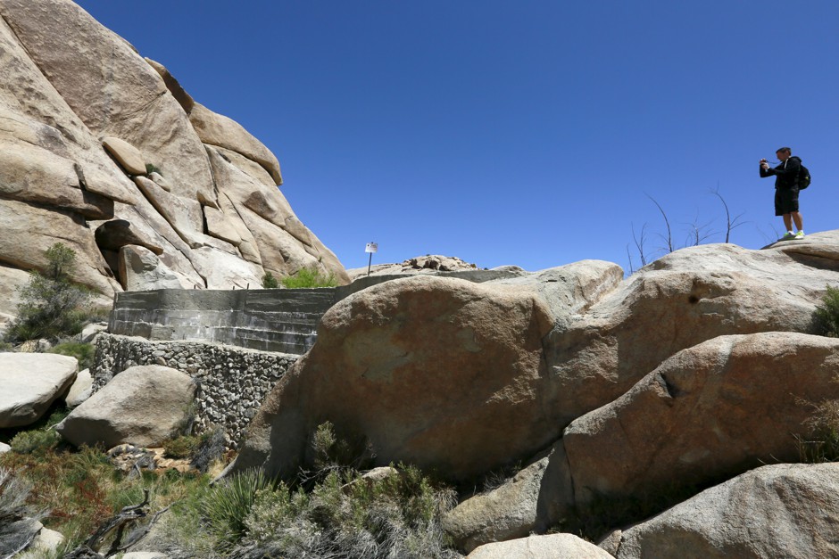 A hiker stands atop Barker Dam in Joshua Tree National Park, one of the parks affected by the proposed fee increase.