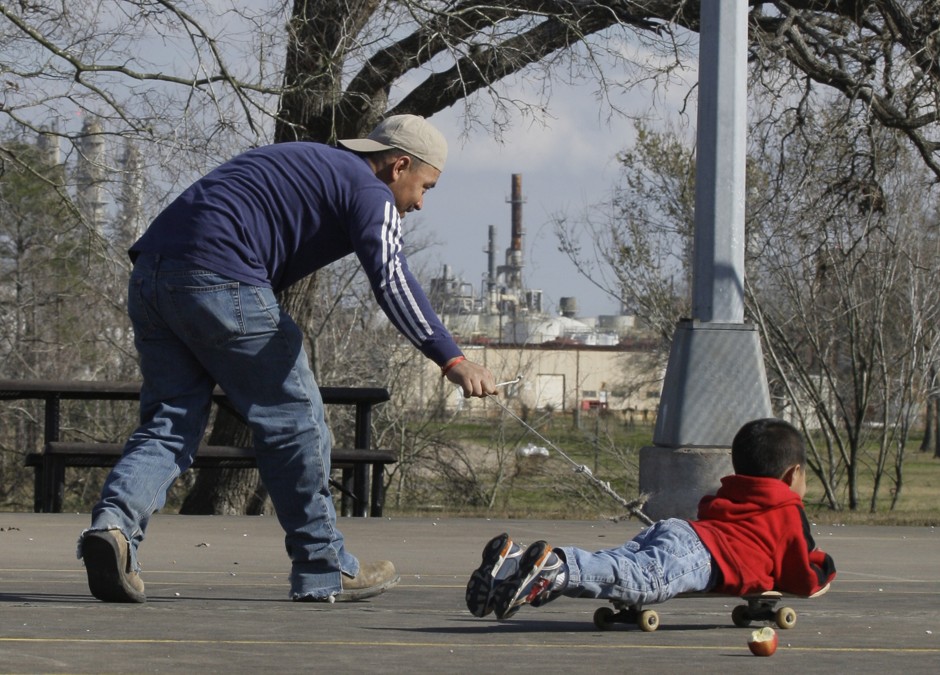 A man plays with a boy at a park across the bayou from a chemical plant in 2010 in Houston. The U.S. Environmental Protection Agency is vastly underestimating pollution spewed by the nation's oil and chemical plants, even though regulators and industry leaders know that more accurate, higher-tech measuring methods have been available for years. 