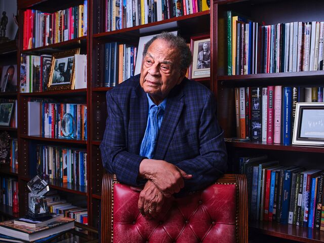 A portrait of Andrew Young leaning on the back of a chair in front of a book shelf. 