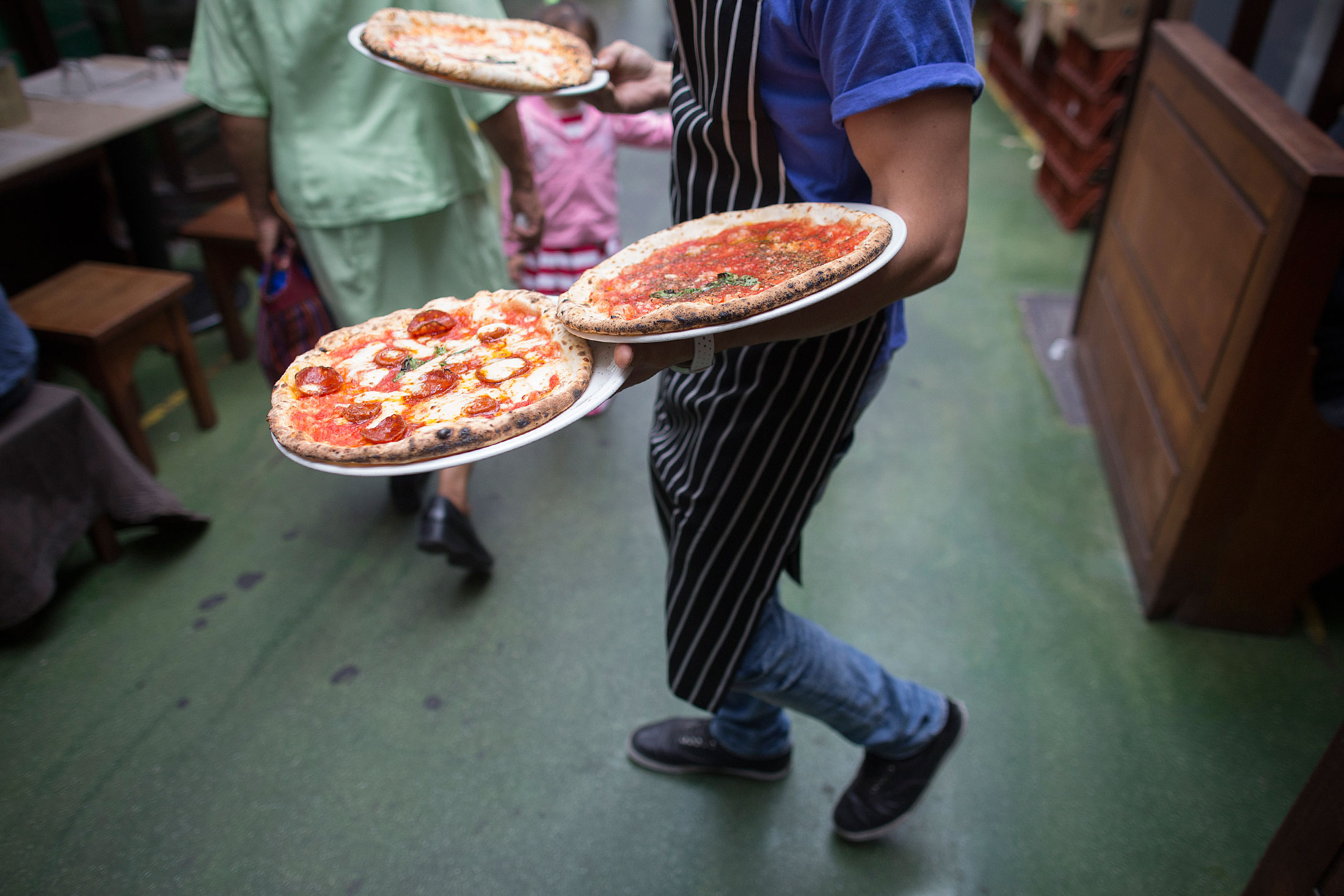 A waiter carries pizzas to customers in a restaurant in Brixton Village, in London, U.K., on Wednesday, Aug. 14, 2013. U.K. services growth accelerated more than economists forecast last month to the fastest pace in more than six years, adding to evidence Britain's economic recovery is gathering momentum.
