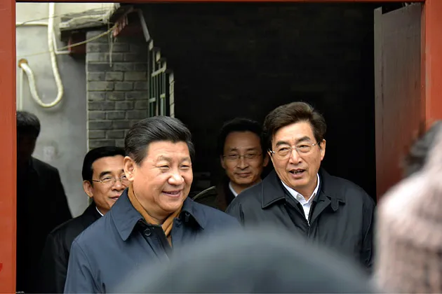 Chinese President Xi Jinping (center left) is accompanied by Beijing's Party Secretary Guo Jinlong (right) during an unannounced visit to a residential alley in Beijing on Feb. 25