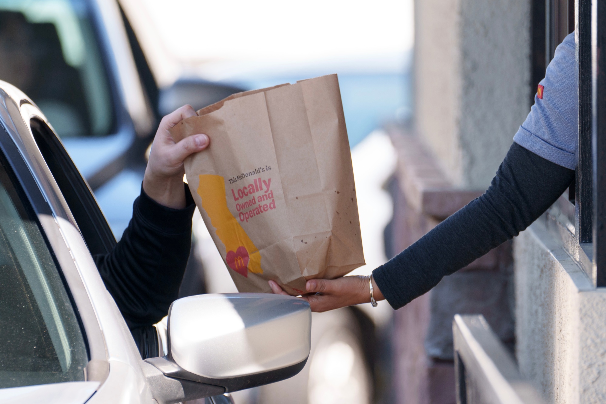 An employee hands a bag to a customer at the drive-thru of a McDonald’s restaurant in Los Angeles on April 1, following California’s wage hike.