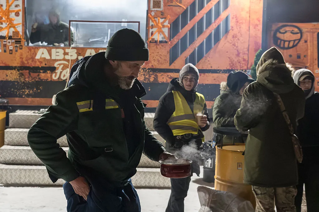 Kyiv residents receive hot meals and warm themselves by an open fire near a mobile kitchen organized by veterans, on Jan. 30.