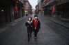 A couple walk on a nearly empty and shuttered commercial street in Beijing on Feb. 12.