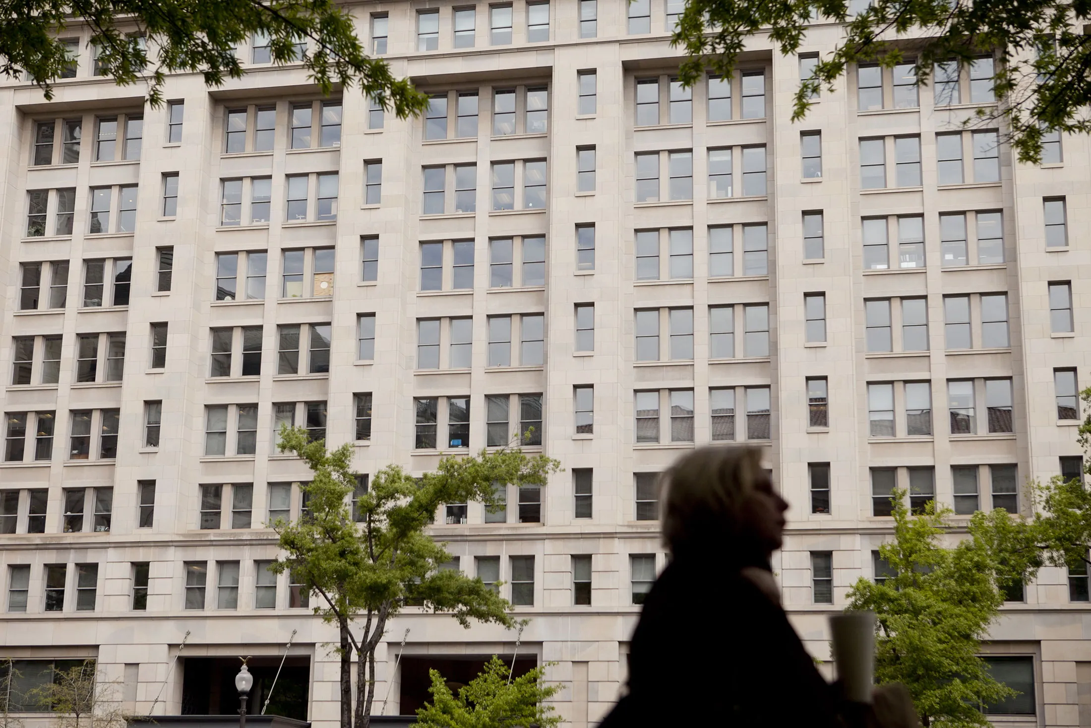 A woman walks past the building that houses the Carlyle Group LP headquarters in Washington, D.C., U.S., on Wednesday, April 11, 2012.

