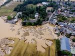 A castle, left, and parts of the village are flooded in Erftstadt-Blessem, Germany, July 17, 2021. Police in western Germany have raided offices and homes in connection with floods last summer in which more than 180 people died and hundreds more were injured. German news agency dpa reported investigations were allegedly focusing on the the owner and lessor of an opencast mine in Erftstadt near the city of Cologne (AP Photo/Michael Probst, File)