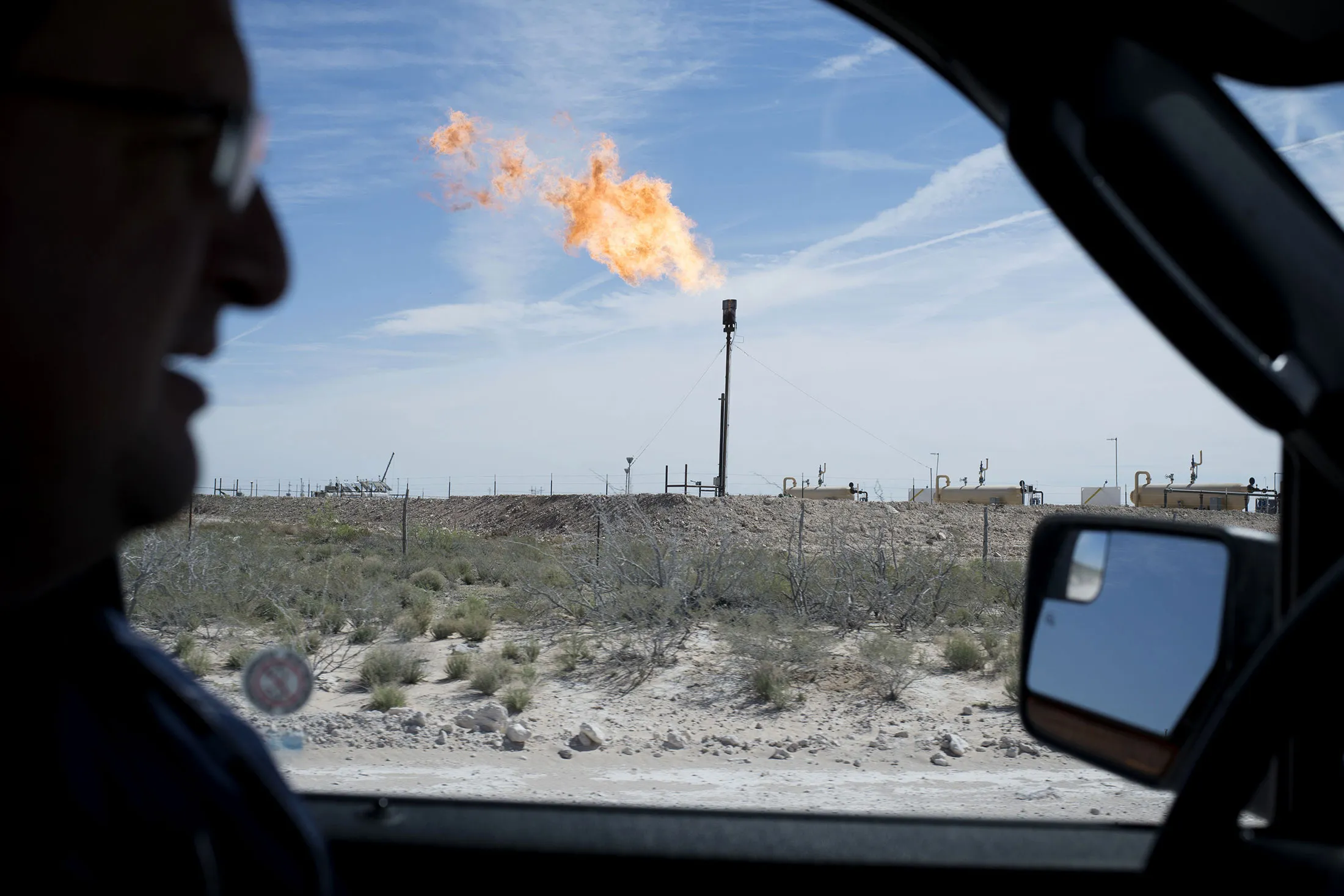 A gas flare is seen through the window as a Royal Dutch Shell Plc representative drives near Mentone, Texas, U.S., on Thursday, March 2, 2017. Exxon Mobil Corp., Royal Dutch Shell and Chevron Corp., are jumping into American shale with gusto, planning to spend a combined $10 billion this year, up from next to nothing only a few years ago.
