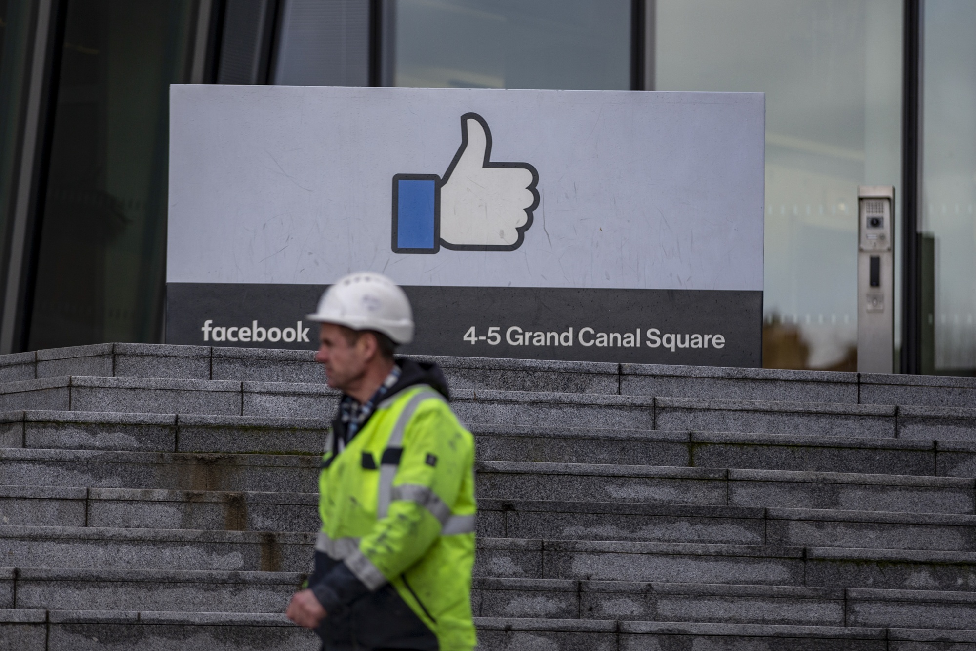 A worker wearing personal protective equipment (PPE) passes a 'thumbs up' logo at the Facebook Inc. European headquarters in Dublin, Ireland, on Monday, Jan. 6, 2020. Ireland issued a record number of passports in 2019 as applications from its citizens in the U.K. surged amid Brexit uncertainty.