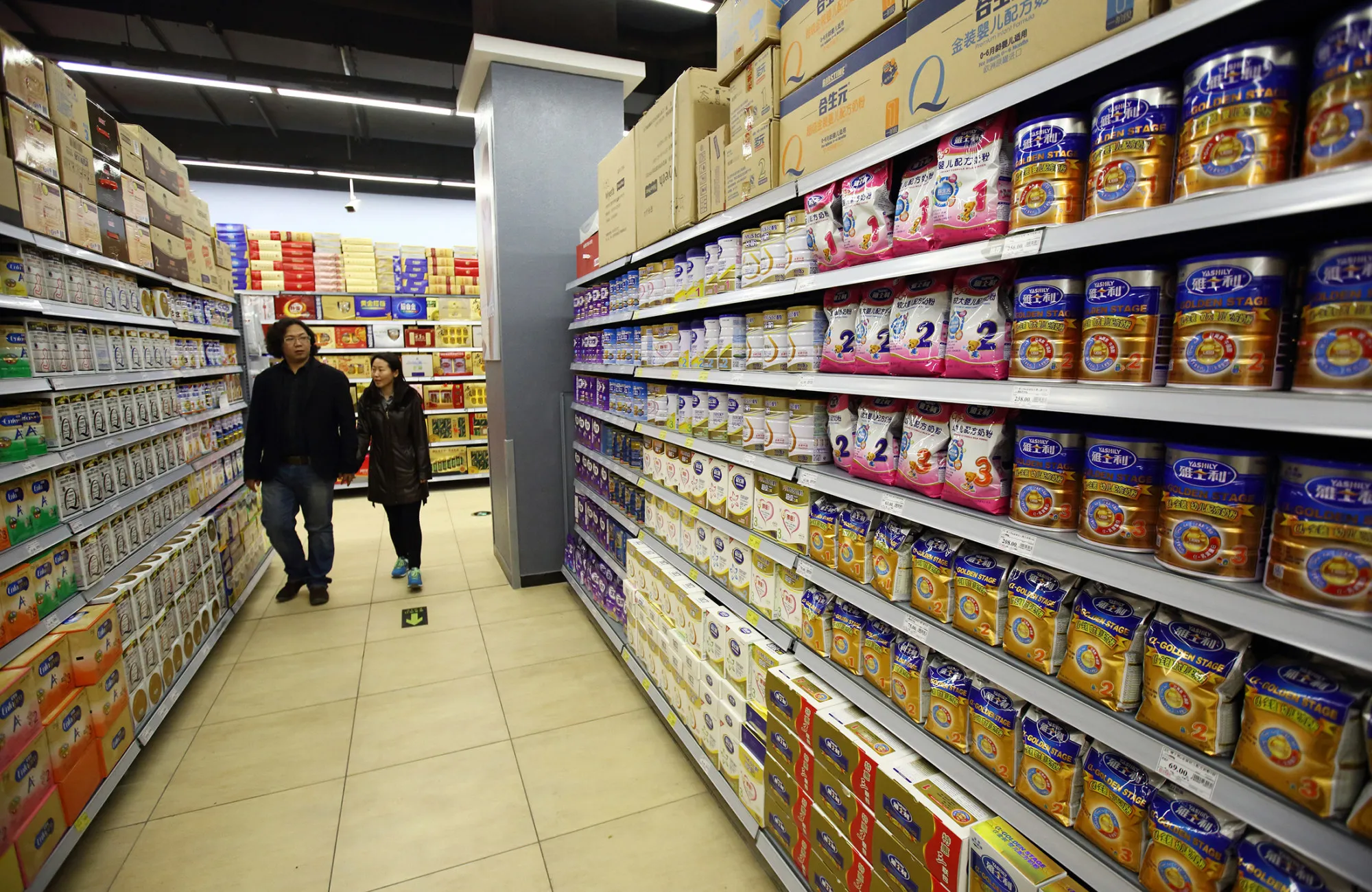 Customers walk down an aisle selling baby formula at a supermarket in Beijing, China, in 2015.
