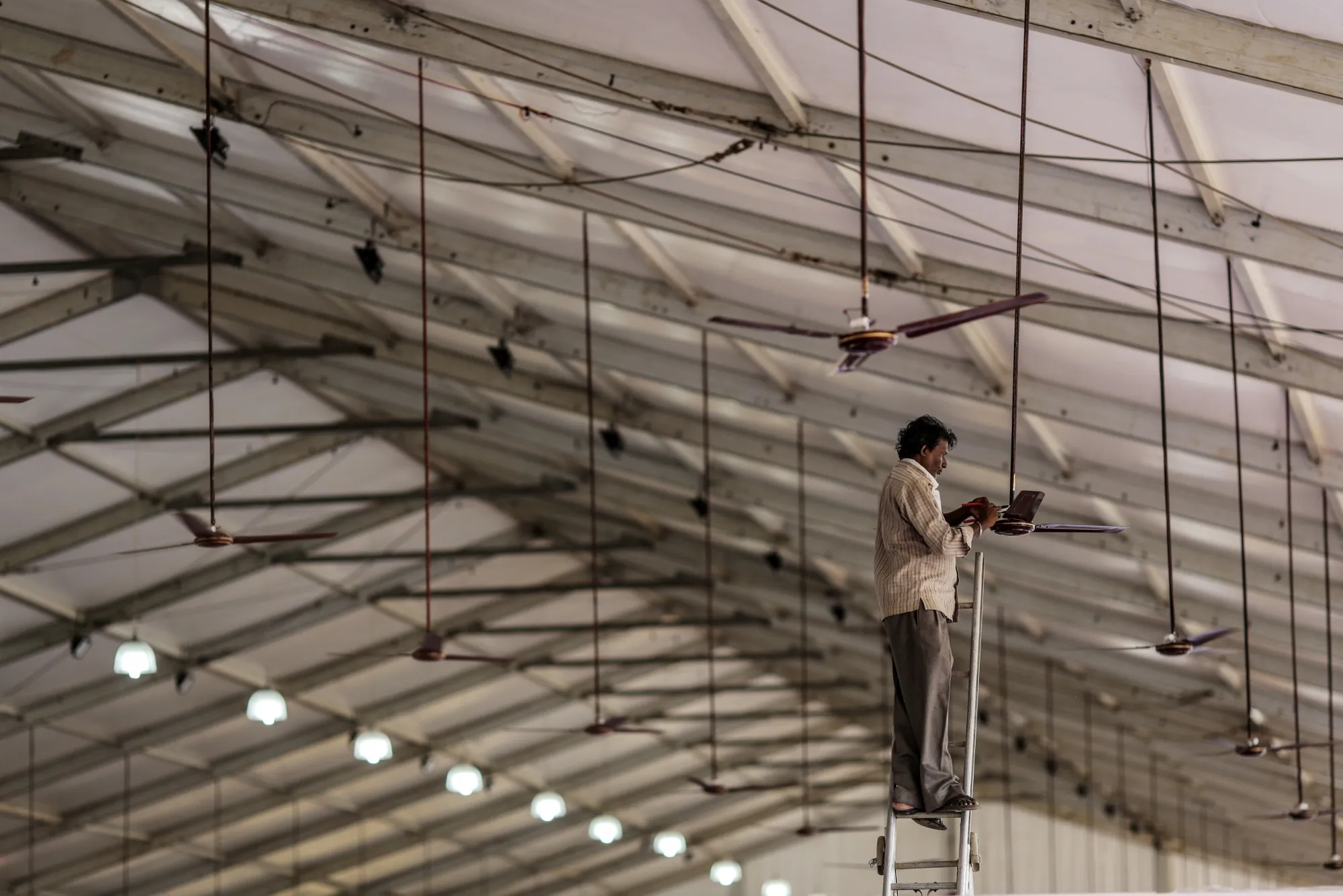 An electrician installs a ceiling fan in Mumbai.