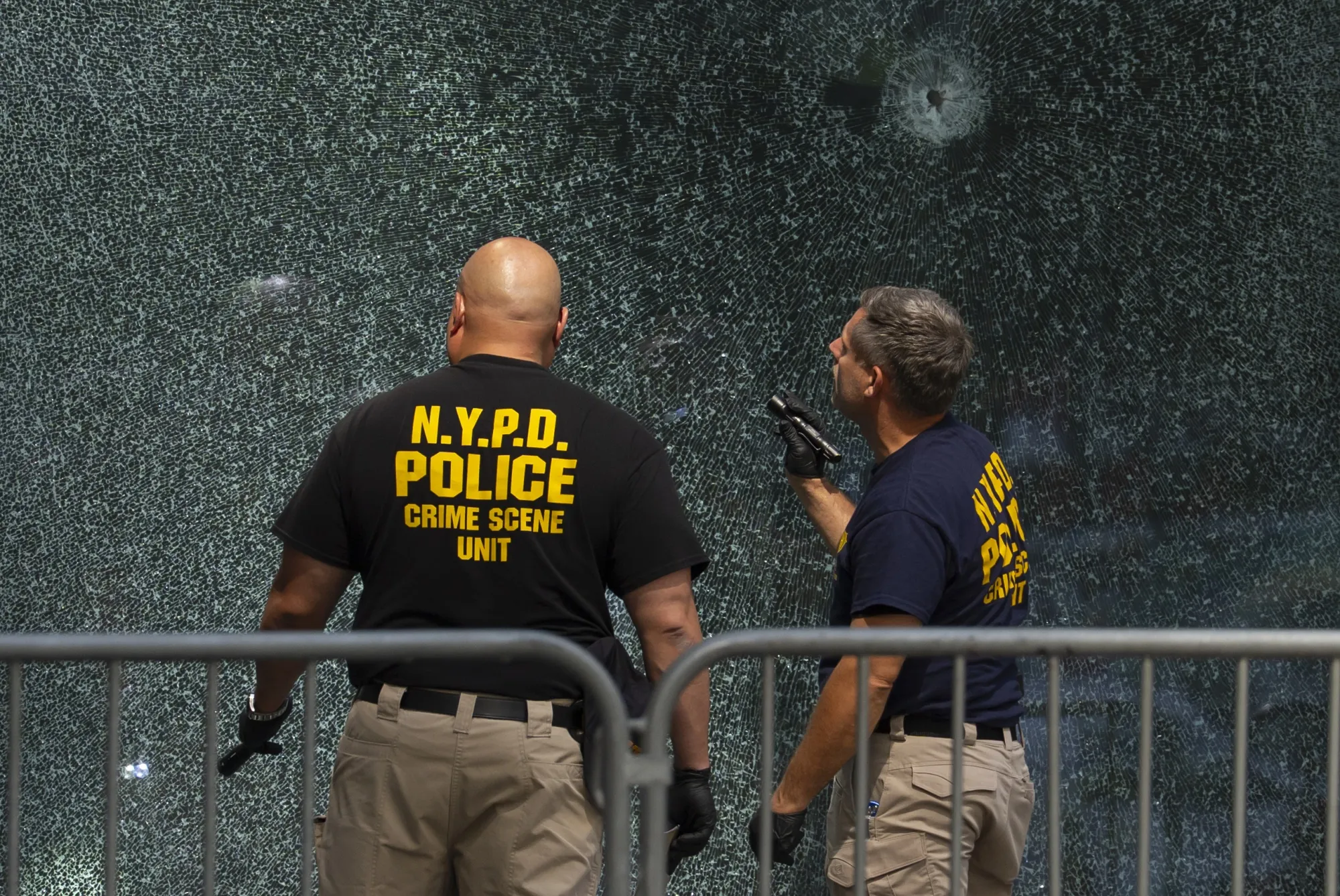 Members of NYPD Crime Unit examine a door with bullet holes at the scene of Monday's deadly shooting, on July 29.