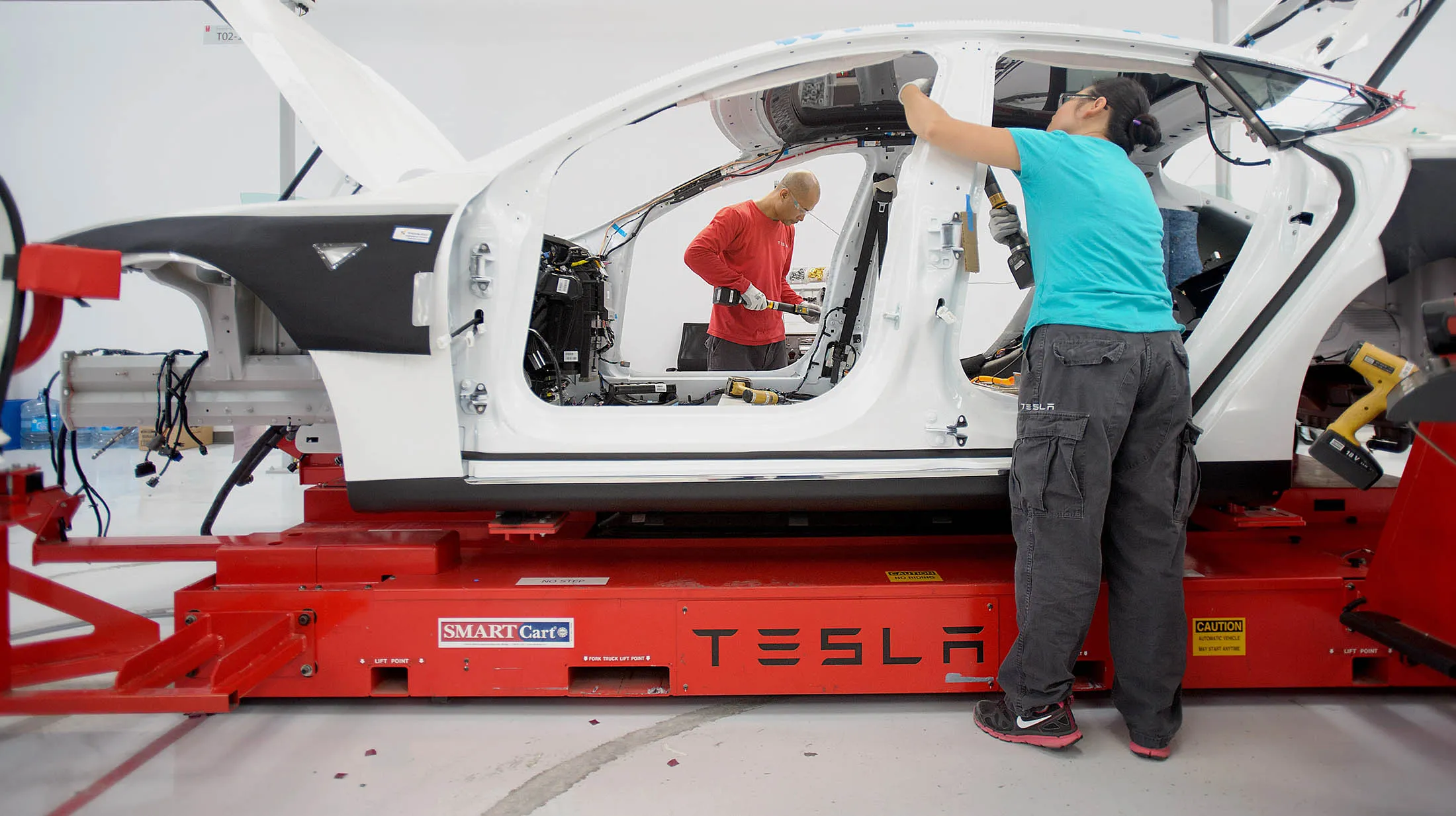 Workers add seat belts to a Model S sedan at Telsa's assembly plant on Wednesday, July 10, 2013, in Fremont, California, U.S.
