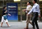 Pedestrians walk past the Mizuho Financial Group Inc. headquarters in Tokyo.