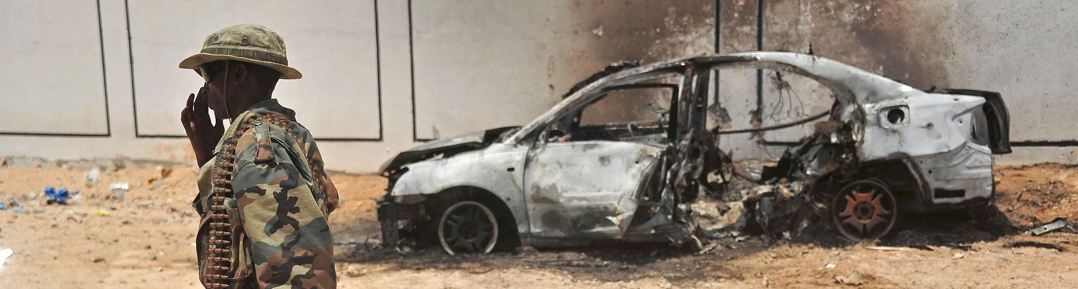 A Somali soldier patrols next to the burnt-out wreckage of a car that was used by suspected al-shabab fighters on April 16, 2017. Somali security forces shot dead two suspected al-shabab militants, an Al-Qaeda linked extremist group, who were said to be involved in firing rockets. / AFP PHOTO / Mohamed ABDIWAHAB (Photo credit should read MOHAMED ABDIWAHAB/AFP/Getty Images)
