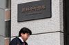 A businessman walks past the offices of the Norinchukin Bank Ltd. in Tokyo, Japan.