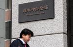 A businessman walks past the offices of the Norinchukin Bank Ltd. in Tokyo, Japan.