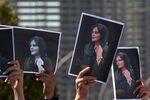 Women hold up signs depicting the image of 22-year-old Mahsa Amini, who died while in the custody of Iranian authorities, igniting demonstrations&nbsp;on the streets&nbsp;of major cities across Iran.