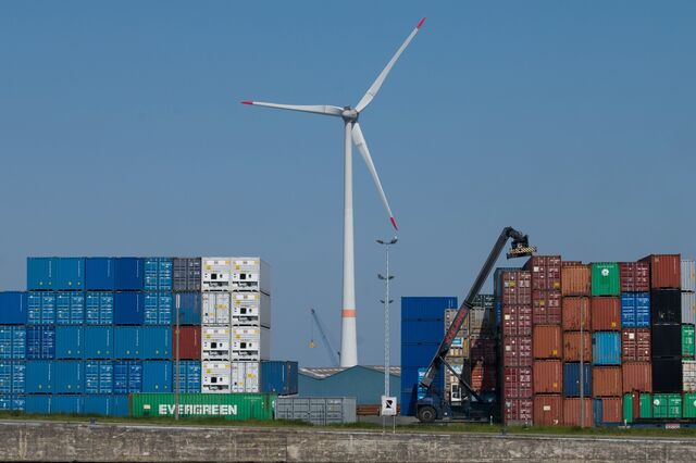 A wind turbine near containers stacked at the newly merged Port of Antwerp-Bruges in Antwerp, Belgium, on Thursday, April 28, 2022.  