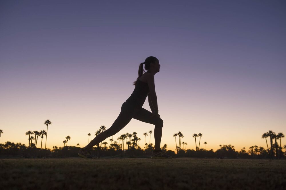 Silhouette of mixed race runner stretching at sunrise