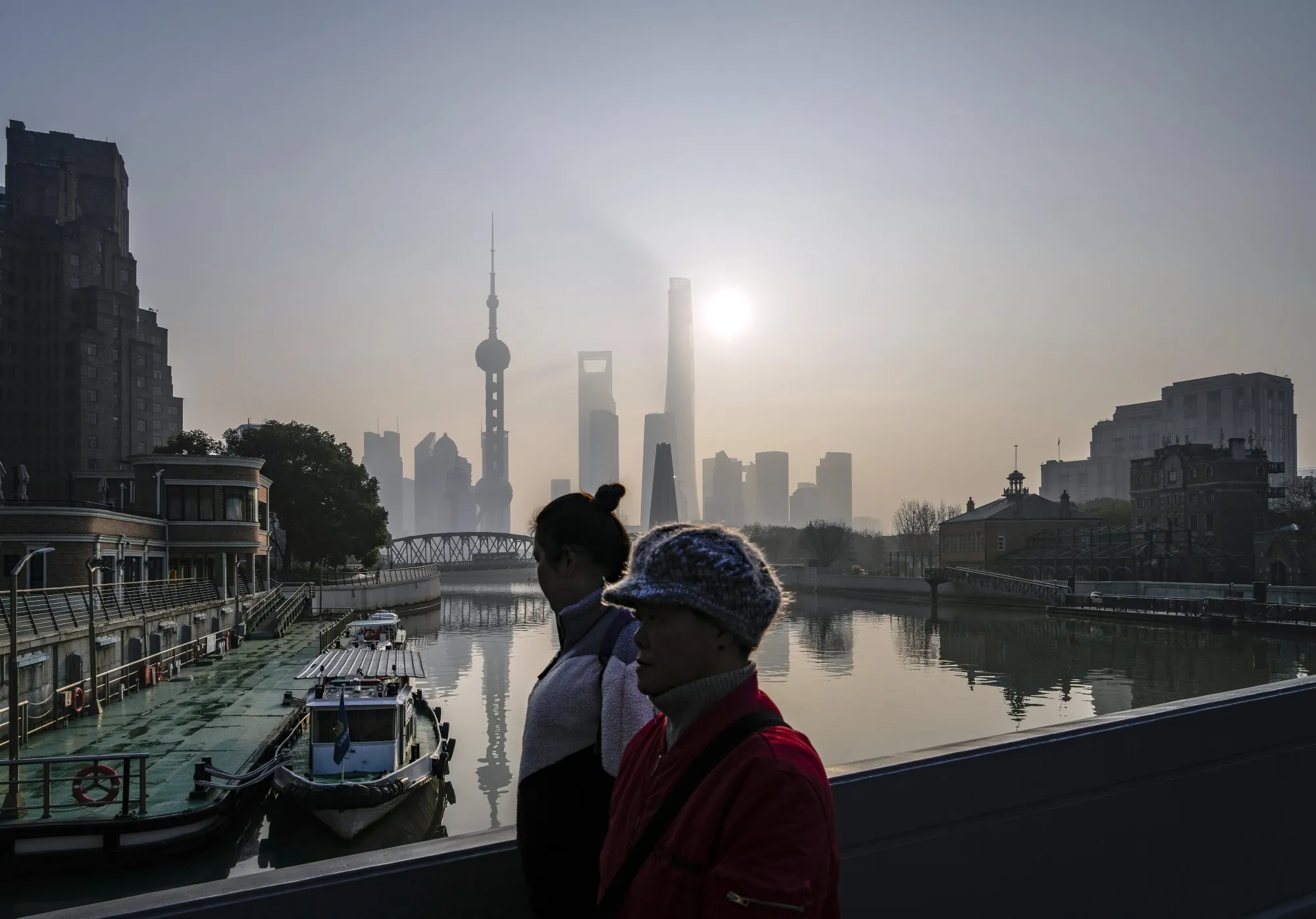 Pedestrians walk along a bridge pass buildings in Pudong's Lujiazui Financial District in Shanghai, China.