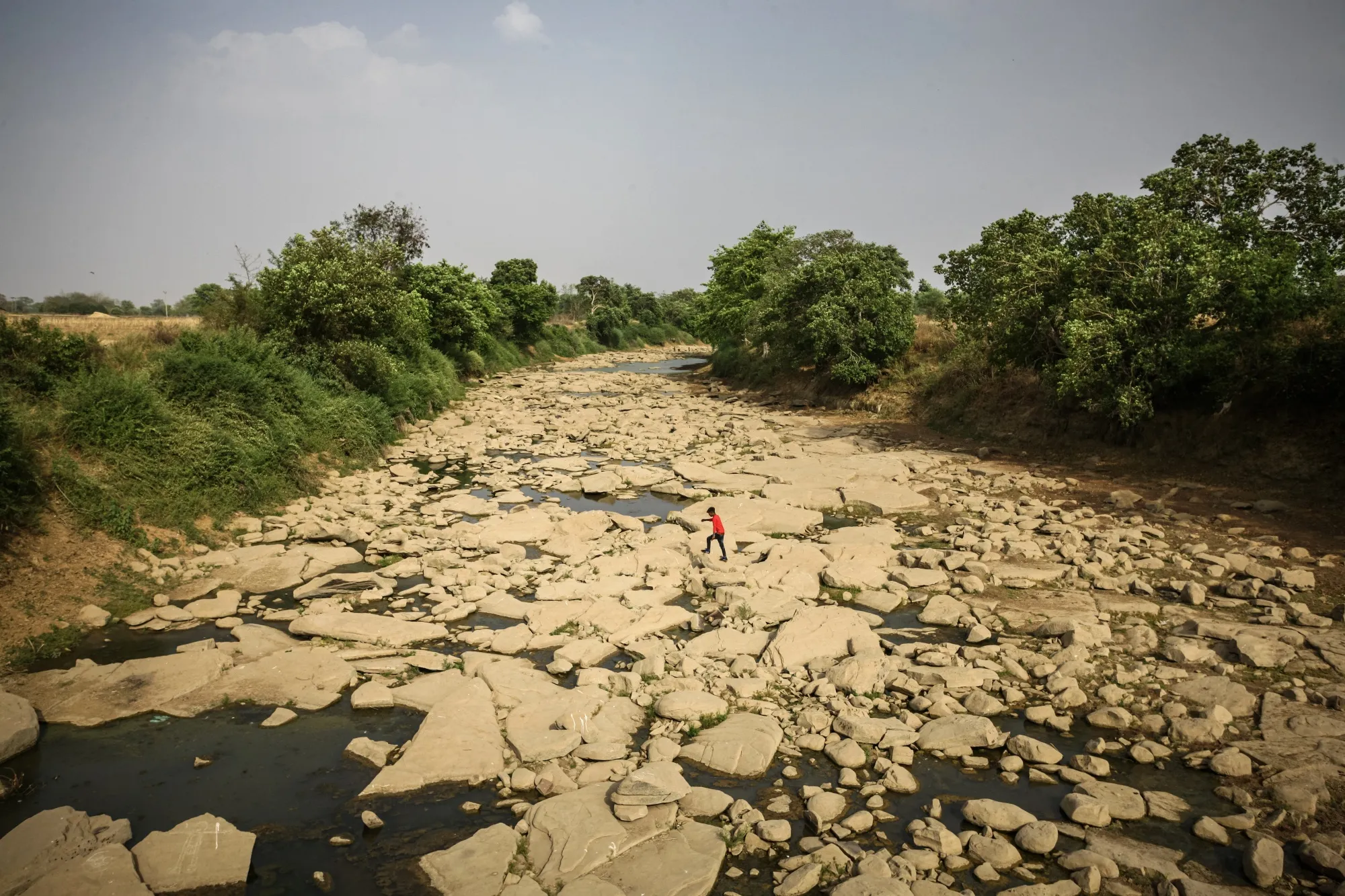 A man walks across the dried bed of the Belan river on May 20.