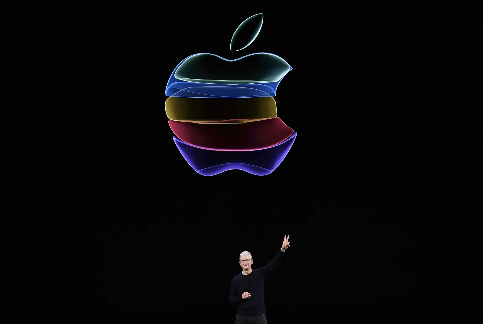 Tim Cook gives a peace sign after speaking during an event.