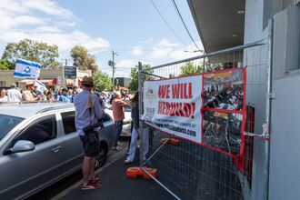 A crowd gathers outside the temporary fence at the burnt