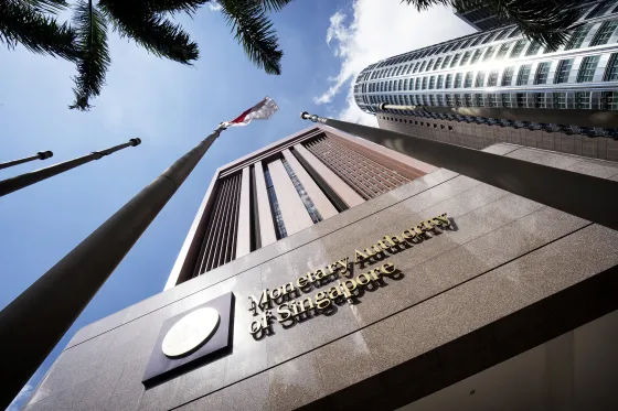 The Singapore national flag flies next to signage for the Monetary Authority of Singapore (MAS) displayed outside the central bank's headquarters in Singapore.&nbsp;
