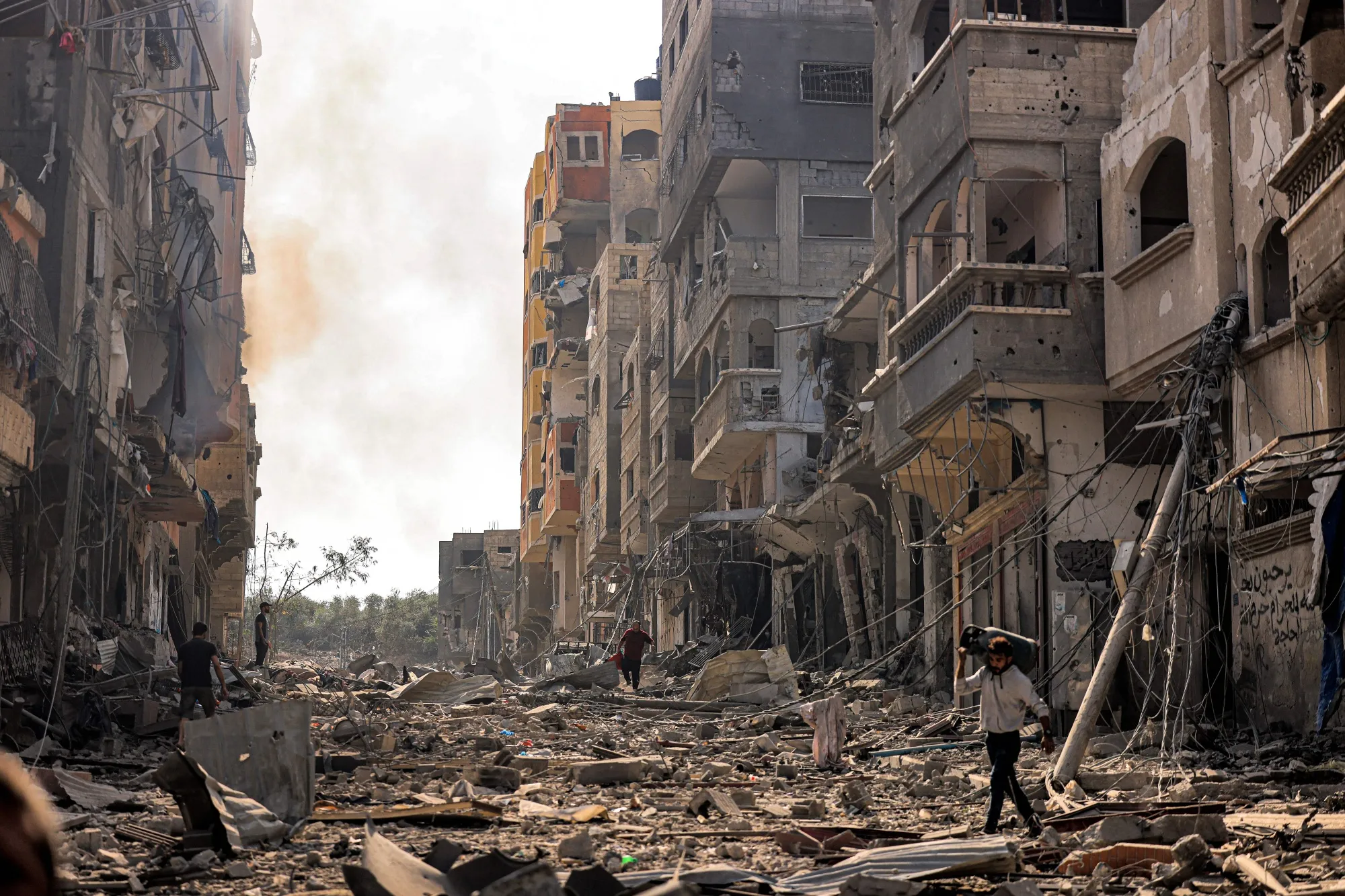 A man carries a propane gas cylinder on his back while walking through debris littering a street in the Jabalia camp for Palestinian refugees in Gaza City.&nbsp;Israel’s campaign to destroy Hamas after the militant group’s surprise incursion and brutal killing&nbsp;of at least 1,300 people last weekend is entering a new, potentially more bloody phase,