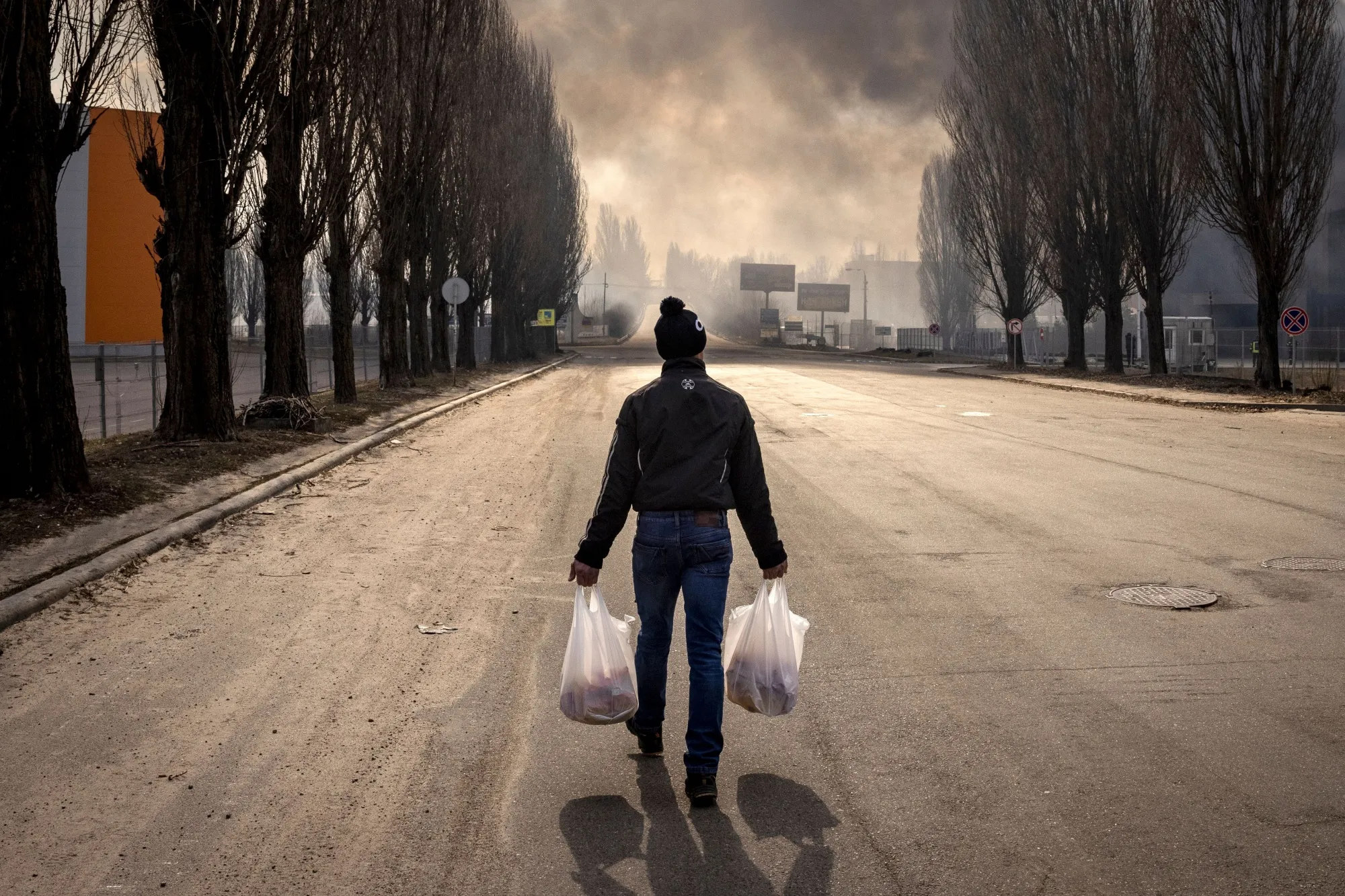 A man walks near a burning warehouse hit by a Russian shell in the suburbs of Kyiv in 2022.
