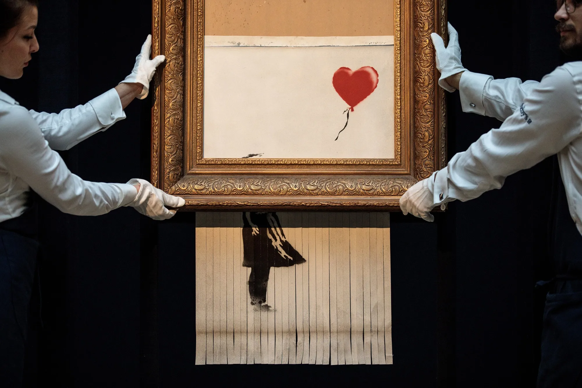 Sotheby’s&nbsp;employees pose with “Love is in the Bin”&nbsp;by British artist Banksy.