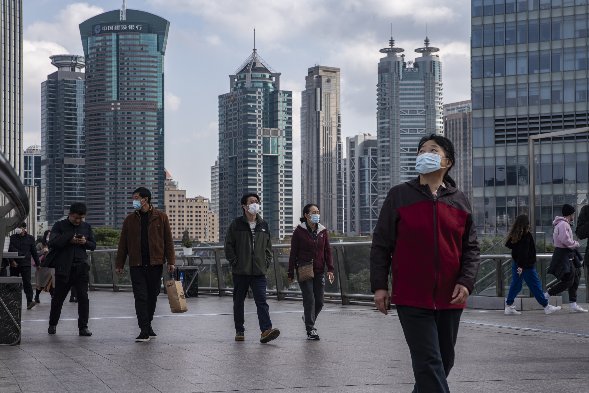 Pedestrians wearing protective masks walk through the Lujiazui financial district in Shanghai.