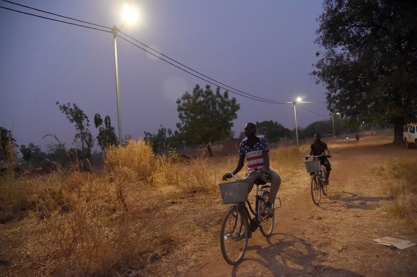 Cyclists ride underneath solar lights in the Takpapieni village in Oti province of northern Togo, Uganda