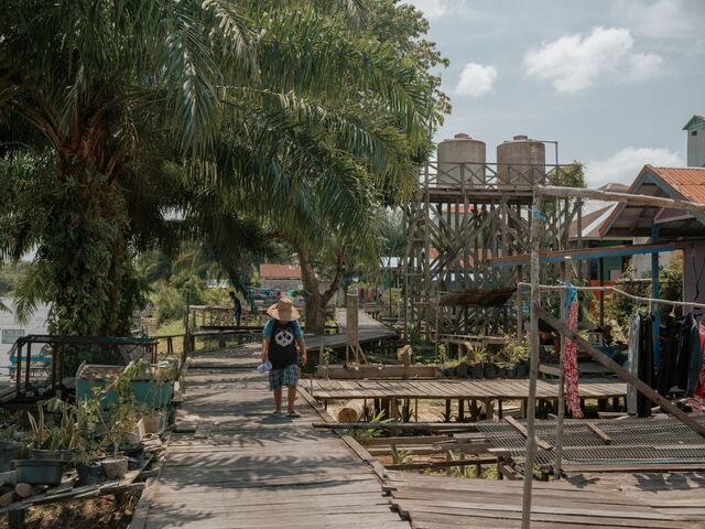 A villager walks along the boardwalk at the river's edge in Muara Dua. Most of the project’s staff have been retrenched since the site’s license was withdrawn.