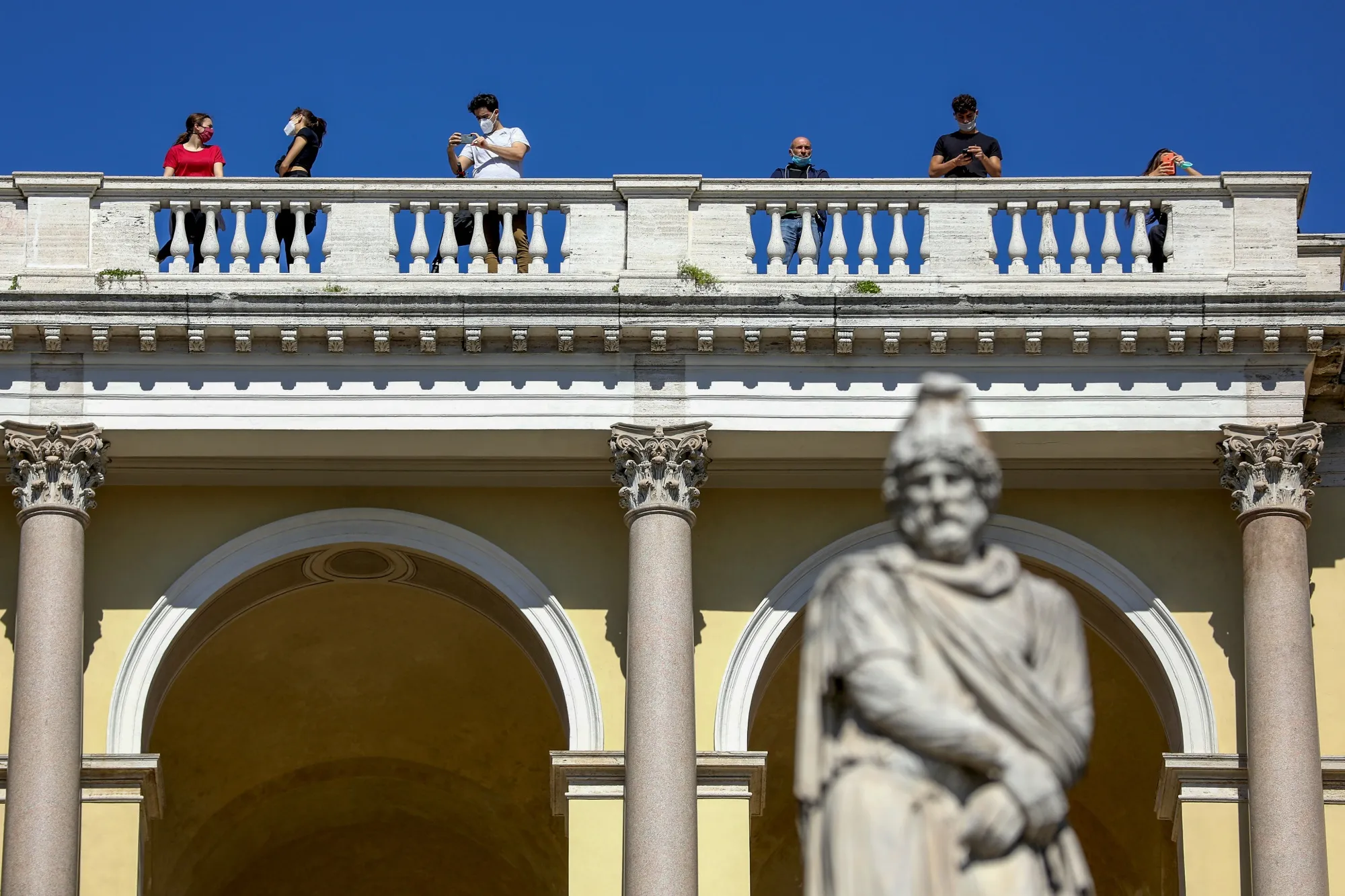 Pedestrian wearing protective face masks look out from Pincio terrace in Rome.