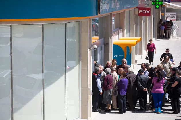 Customers queue outside a Bank of Cyprus branch ahead of its opening for the first time in two weeks in Nicosia on March 28