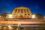 A double-decker bus leaves light trials as it passes the Bank of England in the City of London.