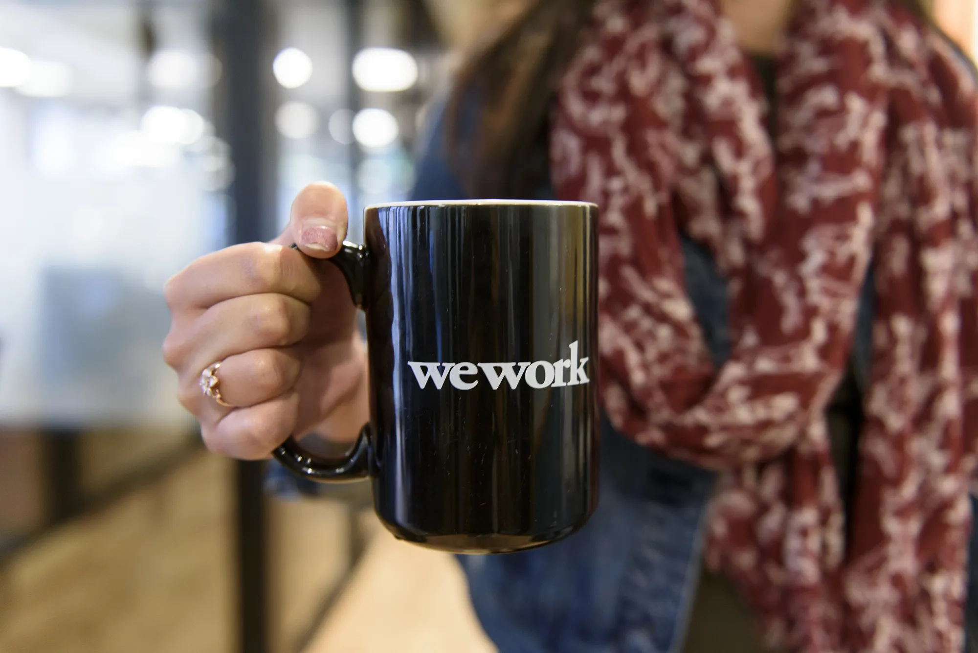A woman displays a WeWork Cos Inc. branded coffee mug for a photograph at the Embarcadero WeWork Cos Inc. offices in San Francisco, California, U.S., on Thursday, Oct. 19, 2017. WeWork has focused its attention on Asia since 2016 with the opening of its first facility in Shanghai amid booming demand for flexible work spaces.