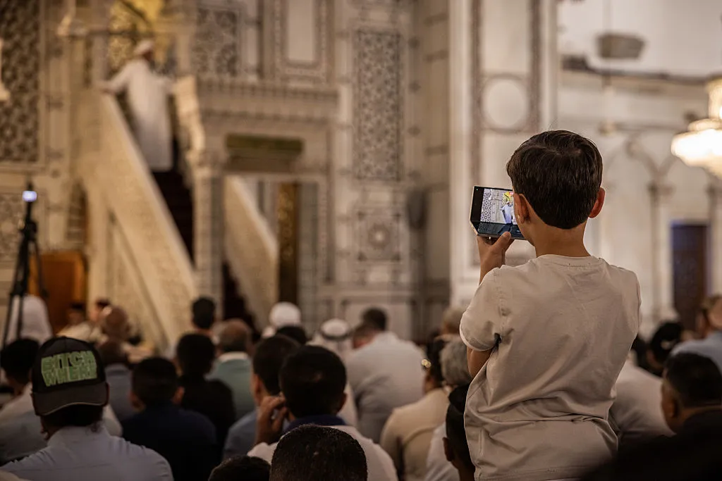 A boy films on a smart phone as cleric gives a sermon in Umayyad Mosque in central Damascus.