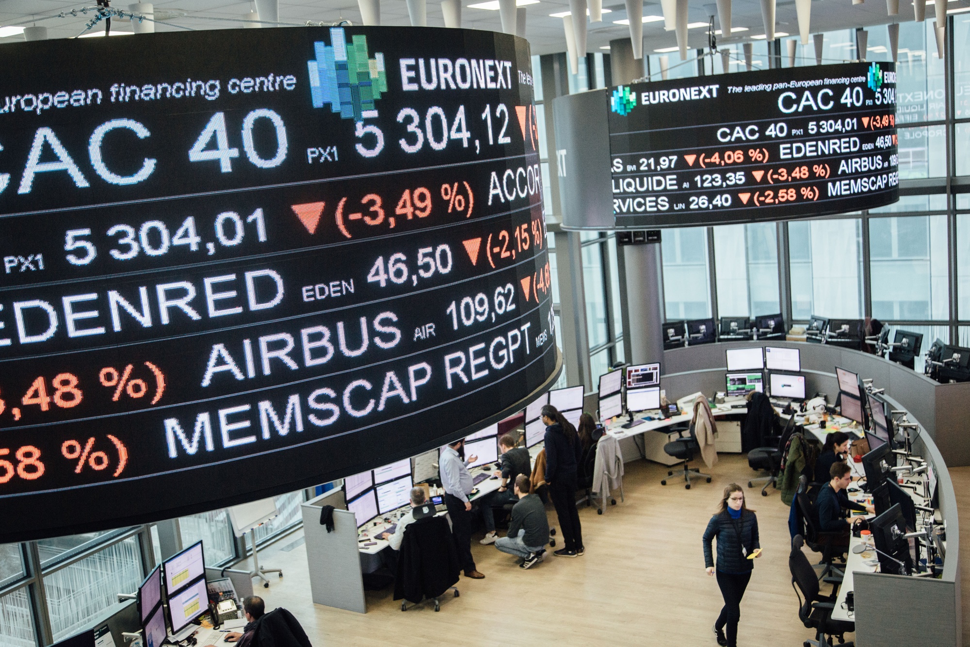 Company trading price movements are displayed on digital screens hanging inside the Euronext NV Paris stock exchange.