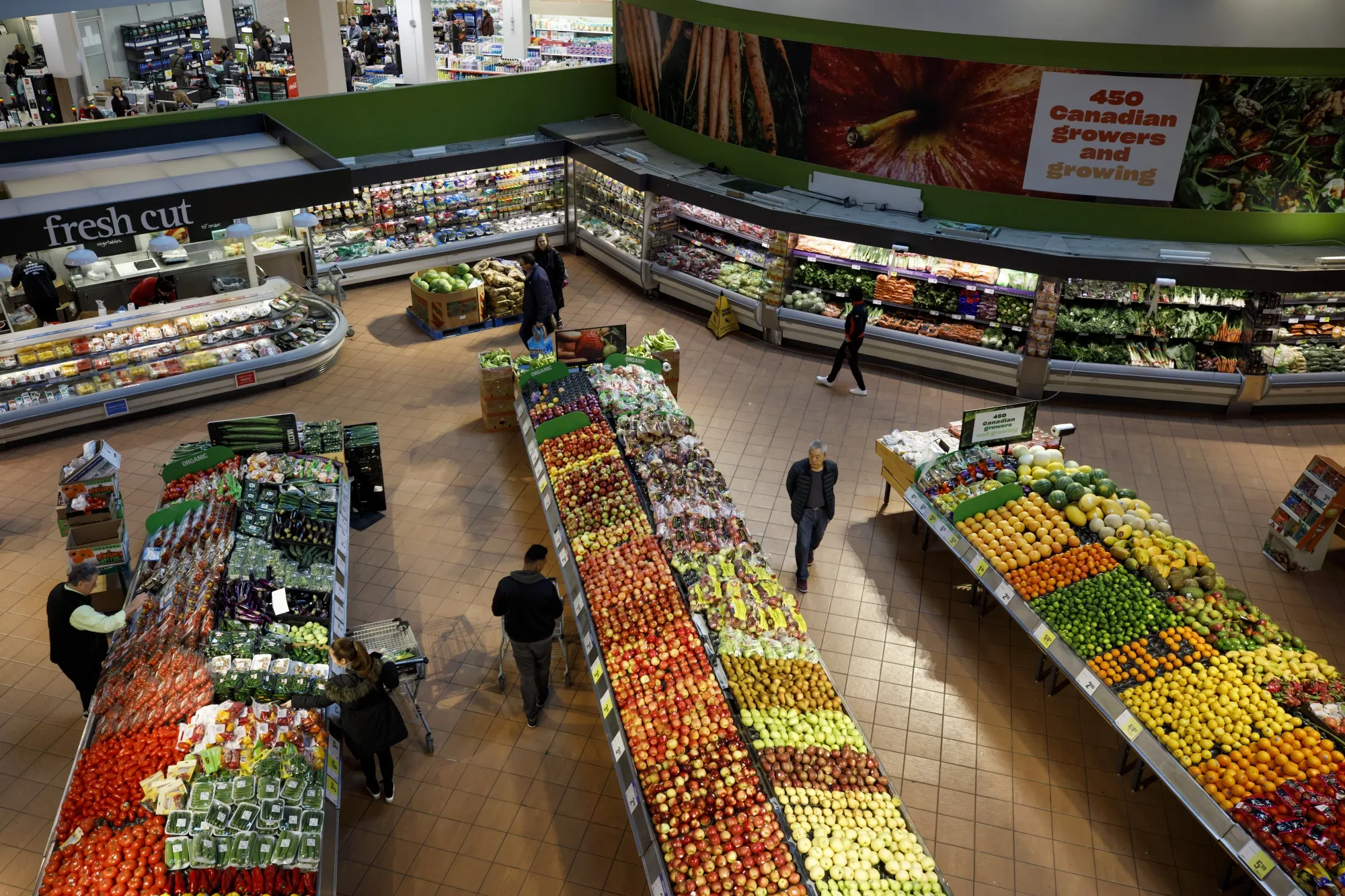 Shoppers browse produce at a Loblaw Cos. grocery store in Toronto, Ontario, Canada.