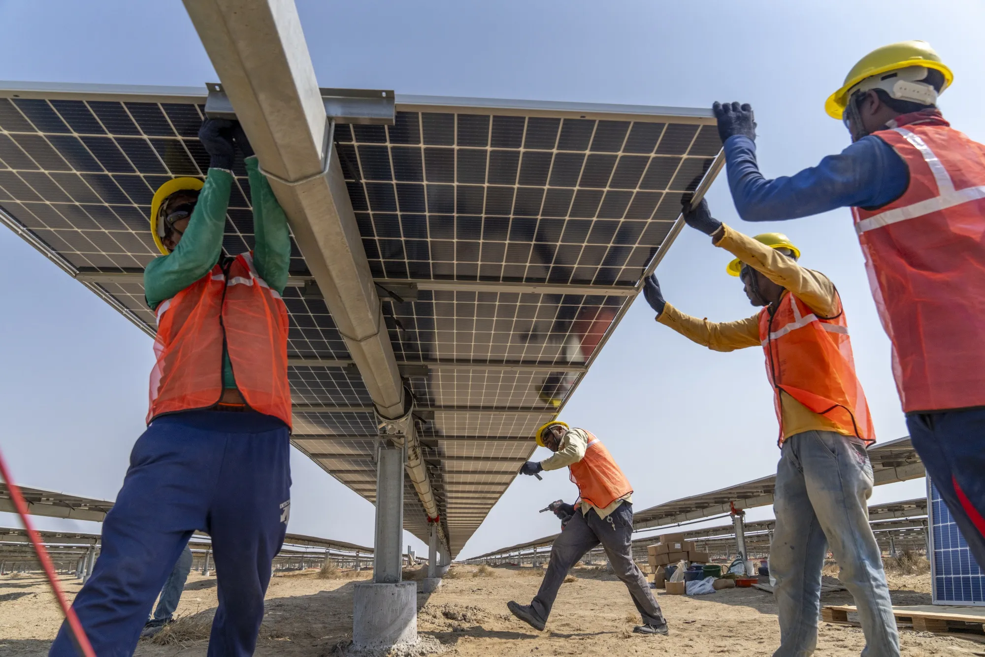 Workers install solar panels at the development site of Adani Green Energy's renewable energy park in Gujarat.