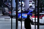 A pedestrian takes a smartphone photograph of Nissan Motor Co. vehicles on display in a showroom at the Nissan Motor Co. headquarters in Yokohama, Japan, on Thursday, Jan. 9, 2020.