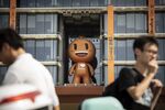 People walk past the mascot for the Taobao e-commerce platform at the Alibaba Group Holding Ltd. headquarters in Hangzhou, China.