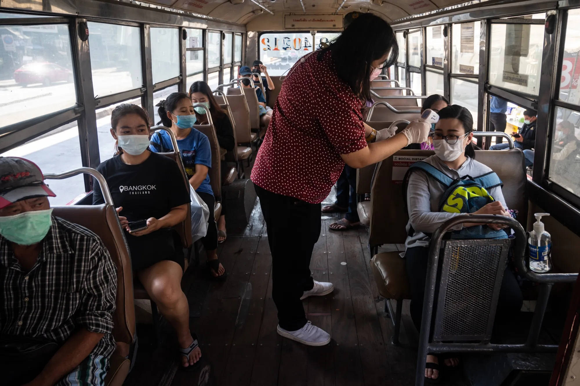 A government official takes body temperature of passengers on the bus at a Covid-19 checkpoint in Bangkok on Jan. 3.