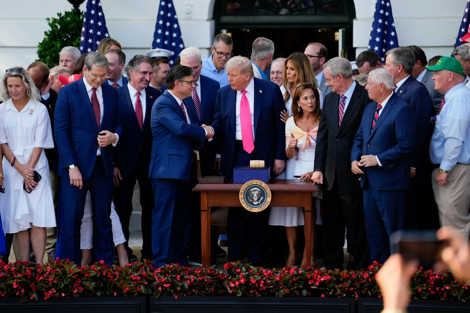 President Donald Trump, center, and House Speaker Mike Johnson shake hands after signing the One Big Beautiful Bill Act at the White House in Washington on July 4.